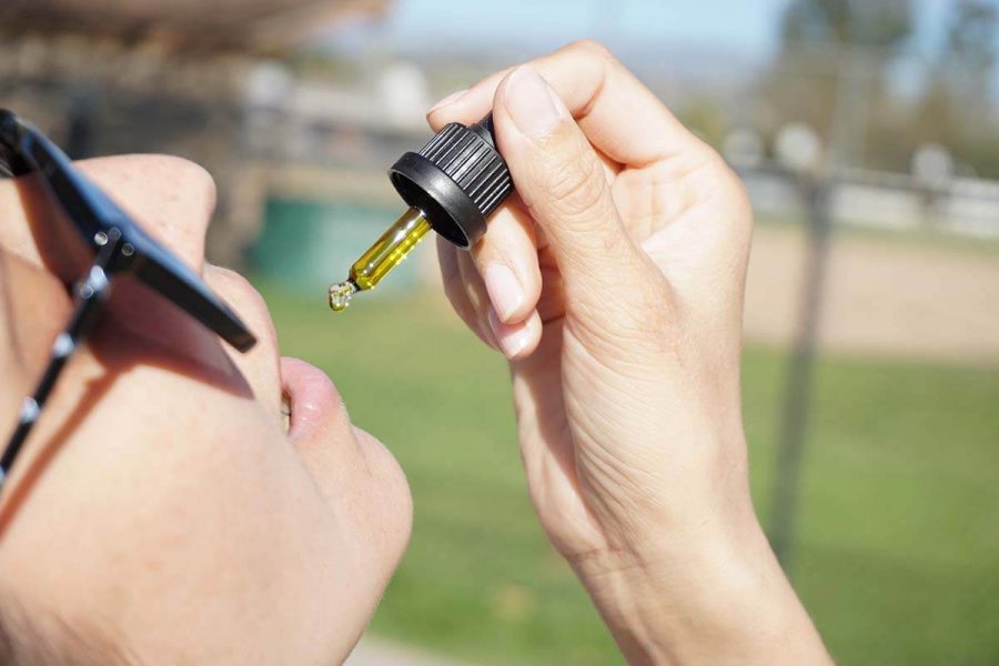 Woman ingesting CBD oil orally, CBD oil may help deal with HIV mouth ulcers