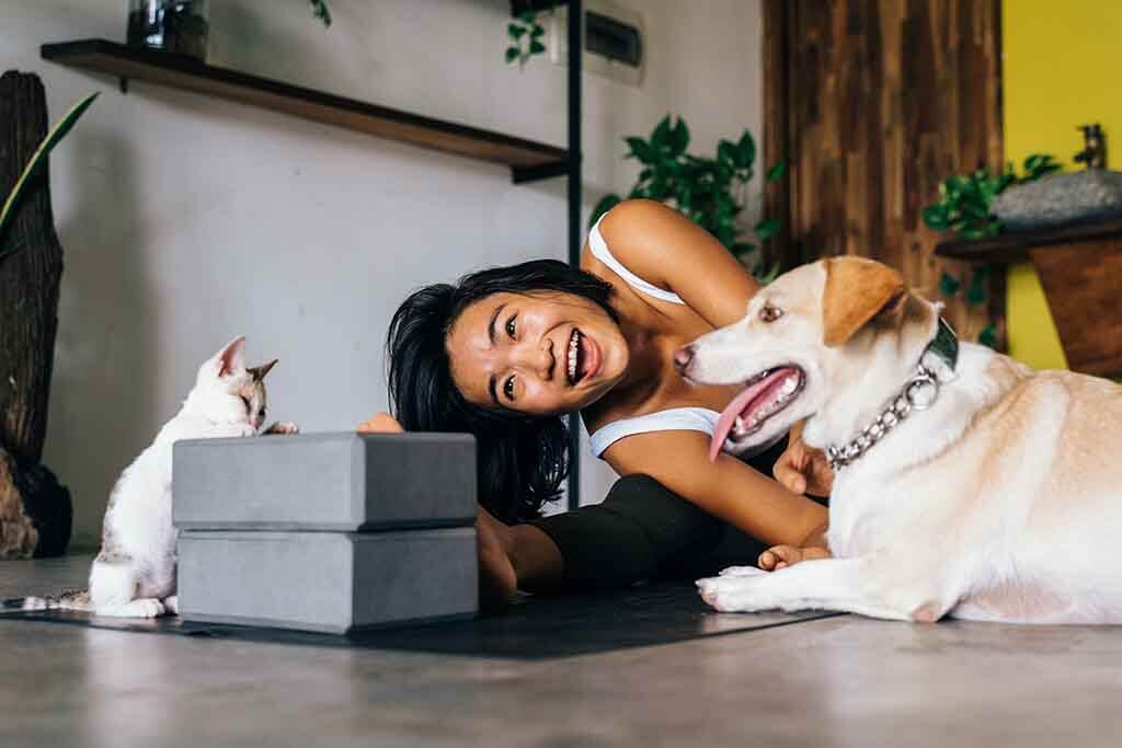 Lady playing with a cat and dog