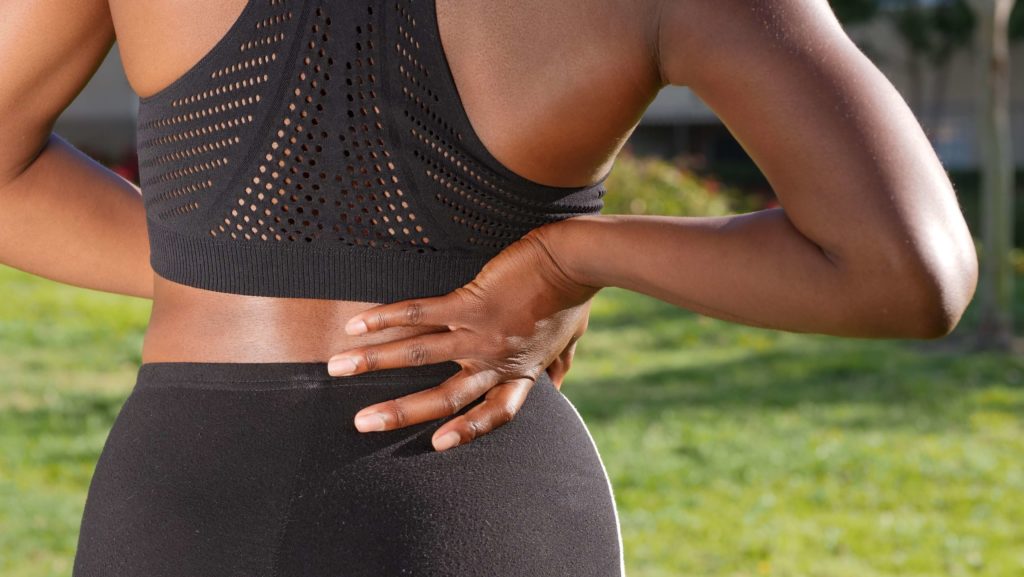 woman with chronic back pain holding her back