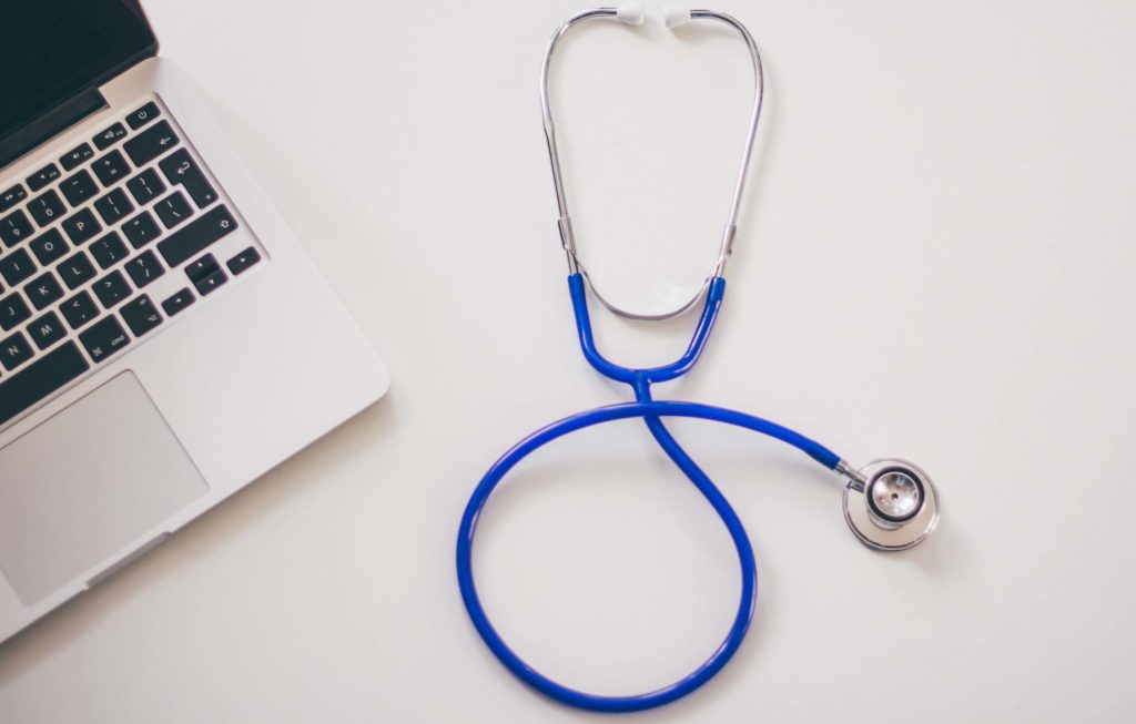 Desk of a medical marijuana doctor with a laptop and stethoscope