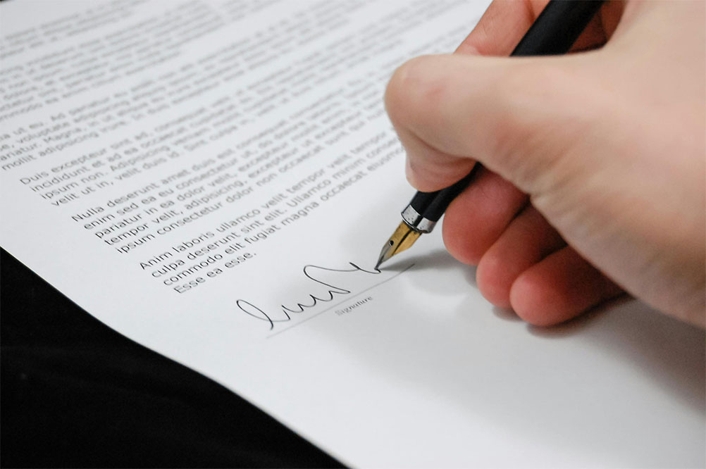 A hand signing a bill into law