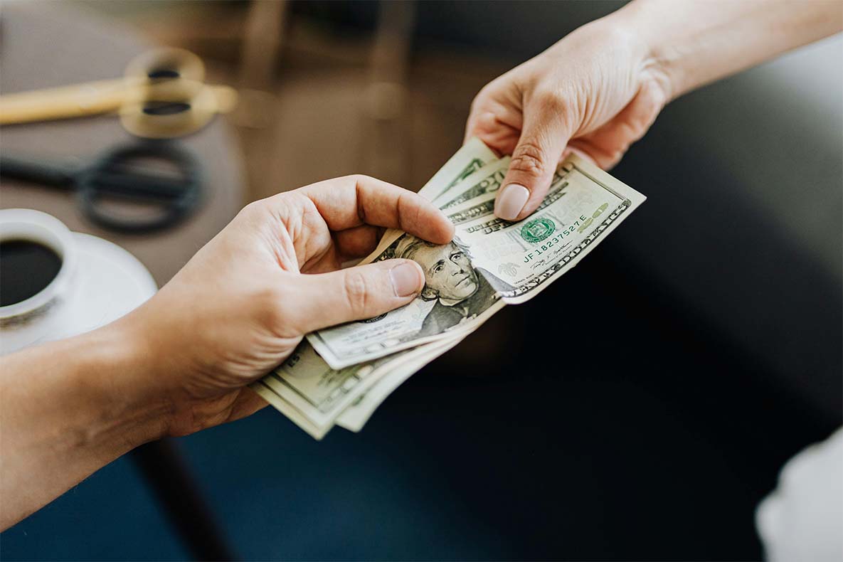 Hand handing over cash and the other receiving for an ounce of weed